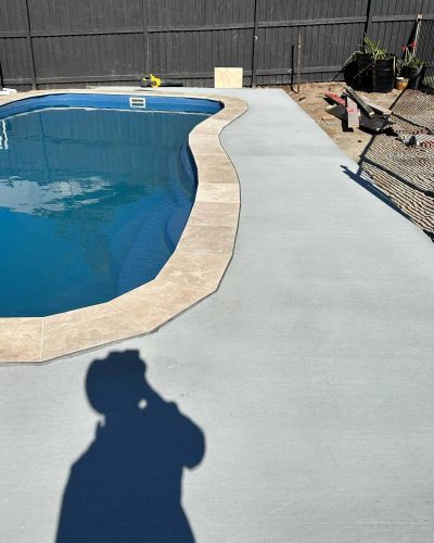 Grey concrete surround and pale coping around a kidney-shaped pool