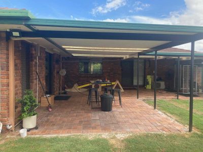 Red brick-paved patio under a pergola behind a brick house