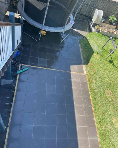 Dark grey tiled path with a border strip running beside a lawn