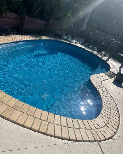 Kidney-shaped pool with brick coping and pale paving, close-up