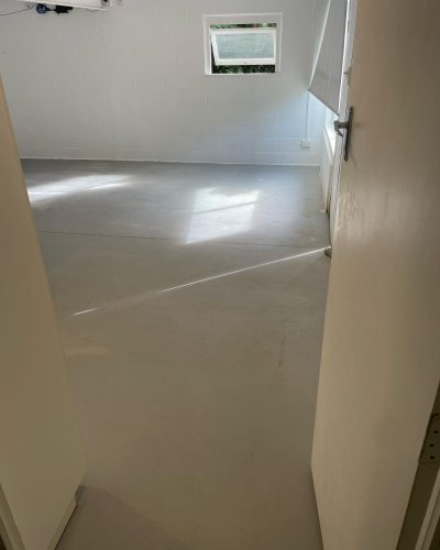 Empty room with large grey floor tiles, seen through an open door